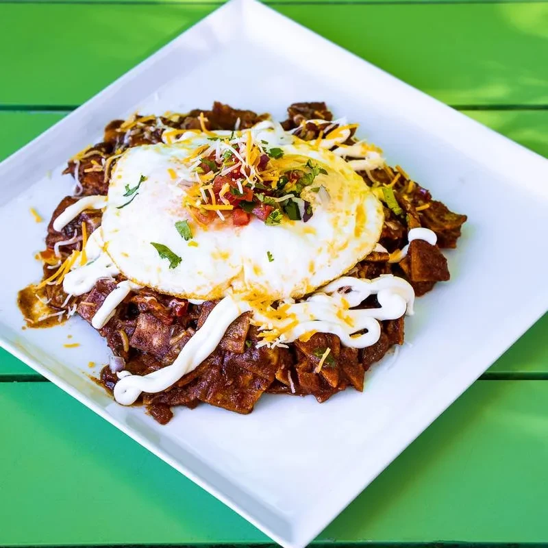 Chilaquiles with two fried eggs, cheese, pico de gallo, and crema.