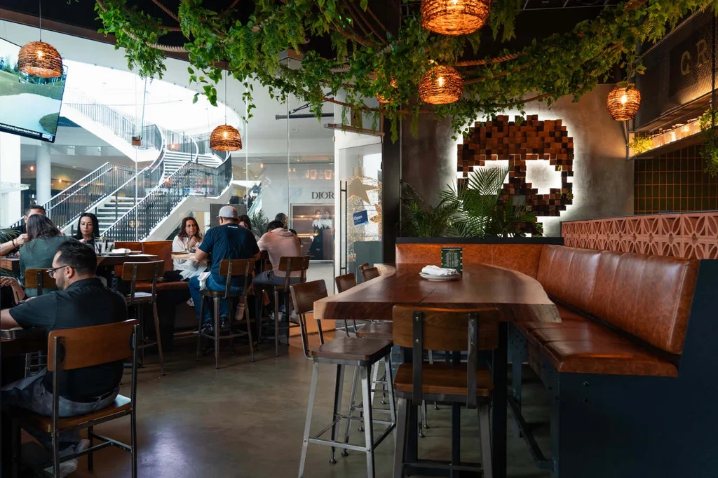 Stylish restaurant with jungle decor, skull art, and modern mall view.