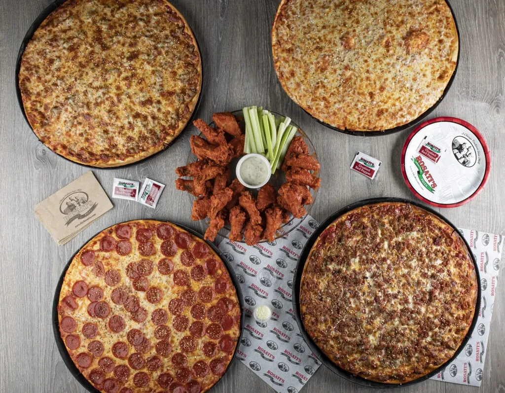 Overhead: Four Rosati's pizzas and chicken wings with celery and dip.