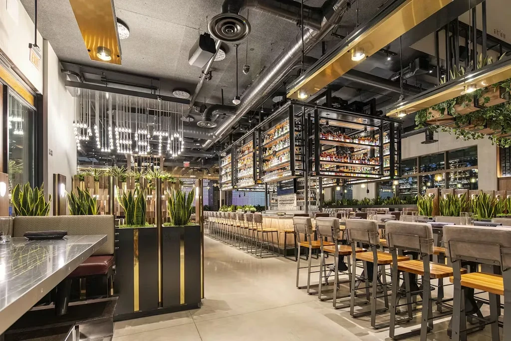 Modern restaurant interior: long bar, dining booths, industrial ceiling, unique chandelier.