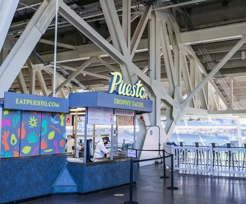 Puesto Trophy Tacos food stand within a modern stadium.