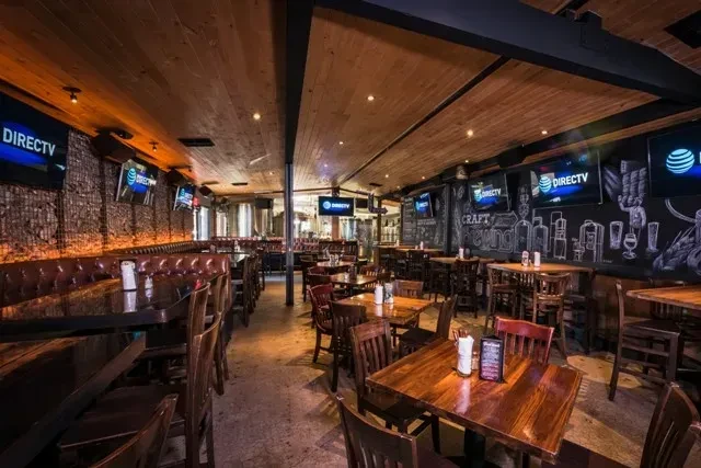 Warm rustic-industrial brewpub interior with brewing tanks and craft brewing chalkboard.