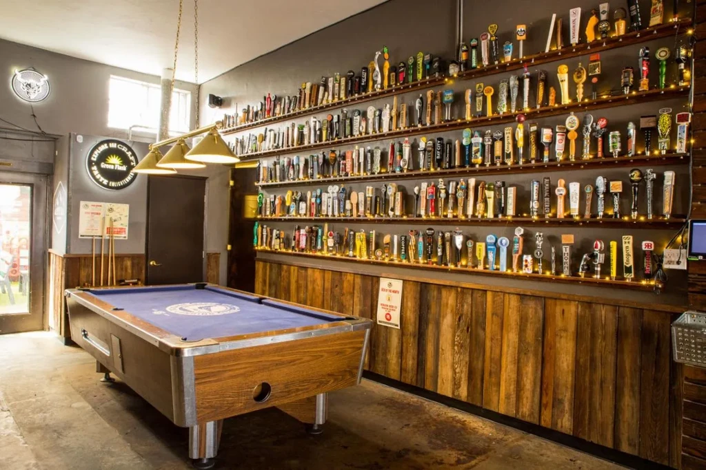 Bar interior with a blue pool table, tap handles, and neon signs.