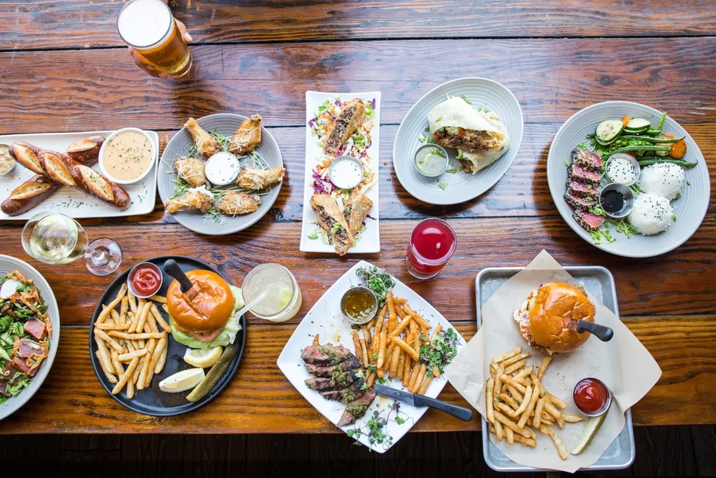 Overhead view of a rustic table overflowing with diverse food and drinks.