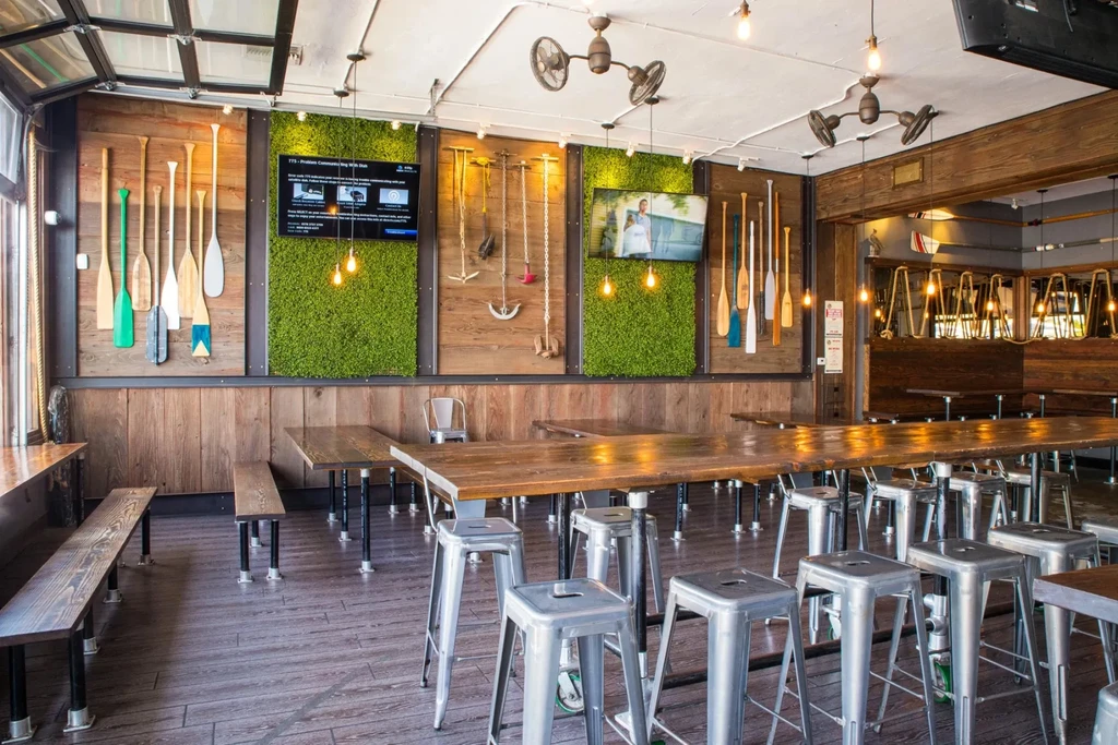 Rustic-industrial restaurant with moss-paneled walls, canoe paddles, and communal tables.