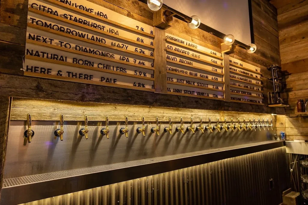 Wall of brass beer taps, menu boards, and reclaimed wood.