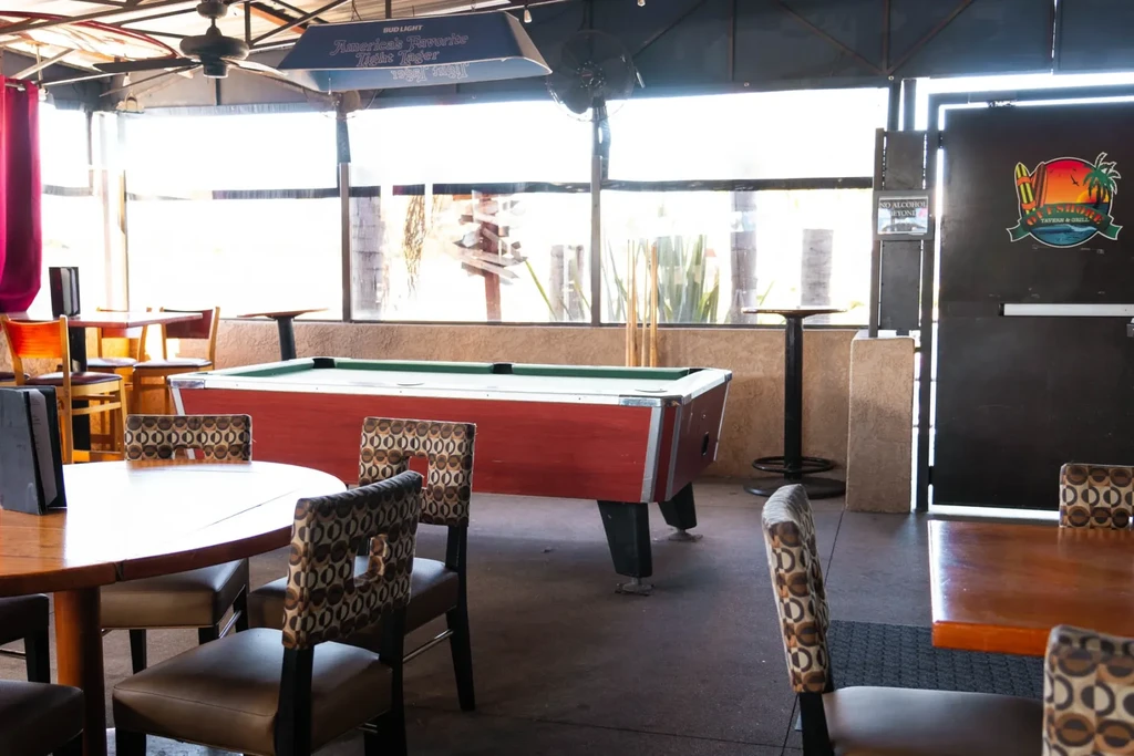 A bright casual bar patio with a red pool table and seating.