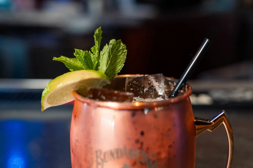 Close-up: copper mug cocktail with lime wedge and mint sprig.