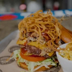 Elaborate burger with shredded meat, crispy onions, and macaroni and cheese.