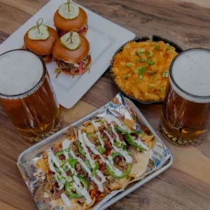 Overhead shot of sliders, mac and cheese, nachos, and two beers.