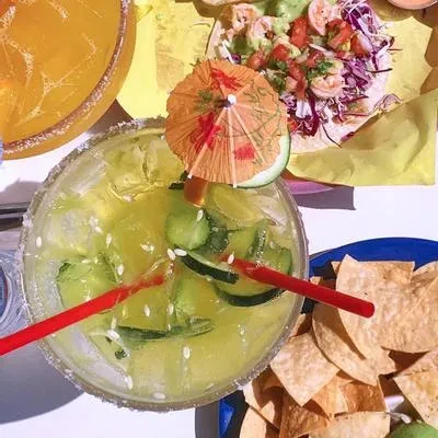 Overhead: green drink with cucumber, shrimp taco, and tortilla chips.