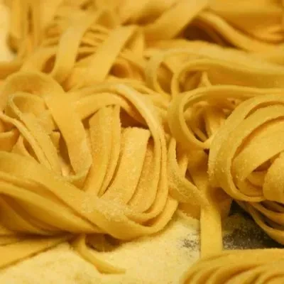 Golden-yellow raw pasta nests, lightly dusted with flour.