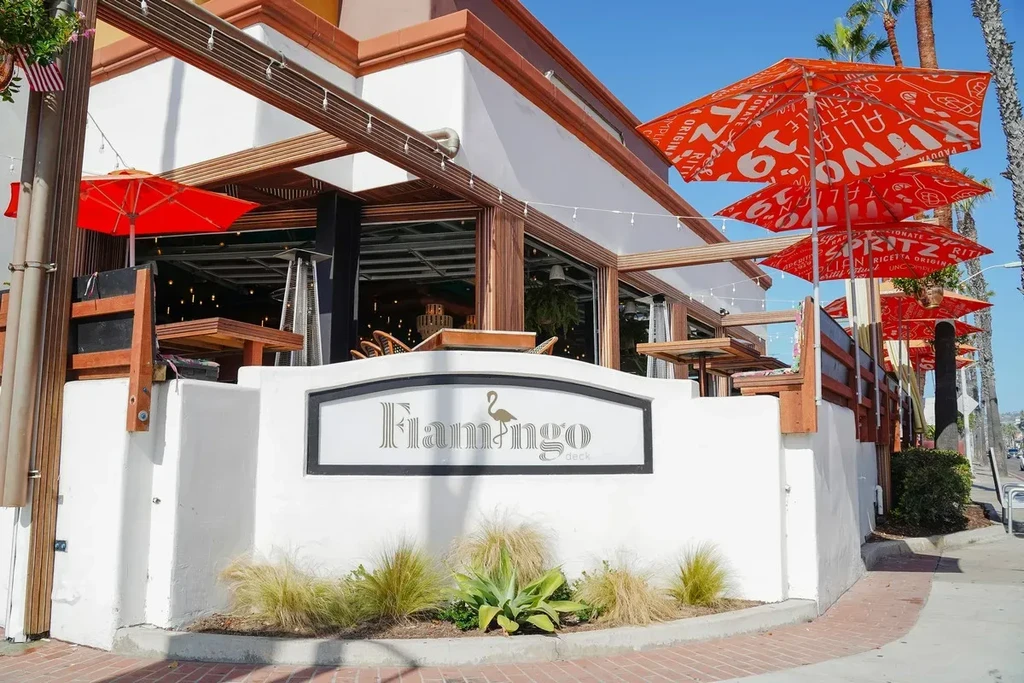 Flamingo Deck restaurant exterior with white stucco, patio, and orange umbrellas.