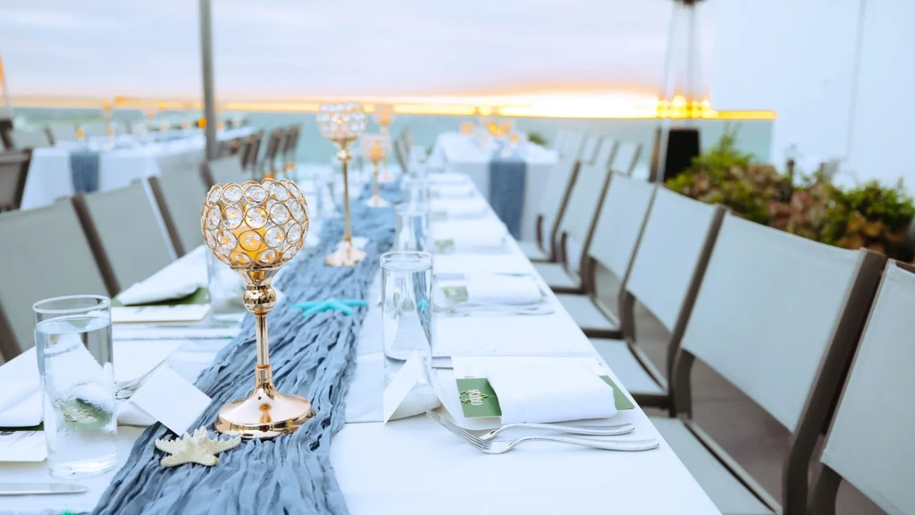 Elegant outdoor dining table with candelabras, starfish, and sunset view.