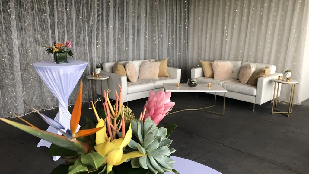 Elegant lounge with modern white sofas, coffee table, and colorful floral arrangements.