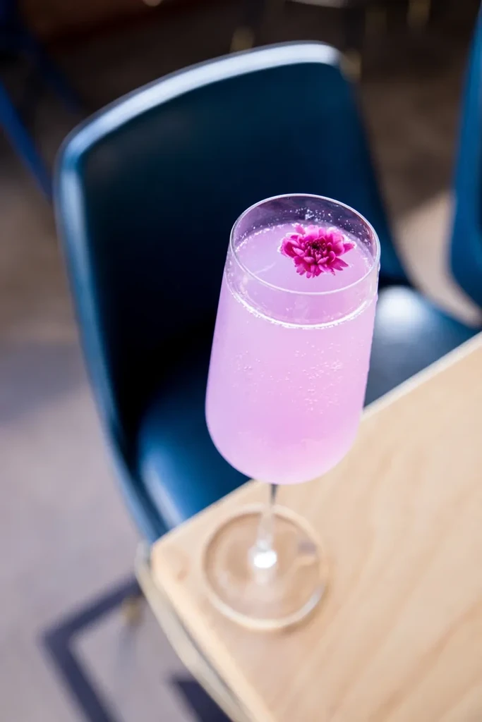 Pink sparkling drink with a fuchsia flower in a stemmed glass.