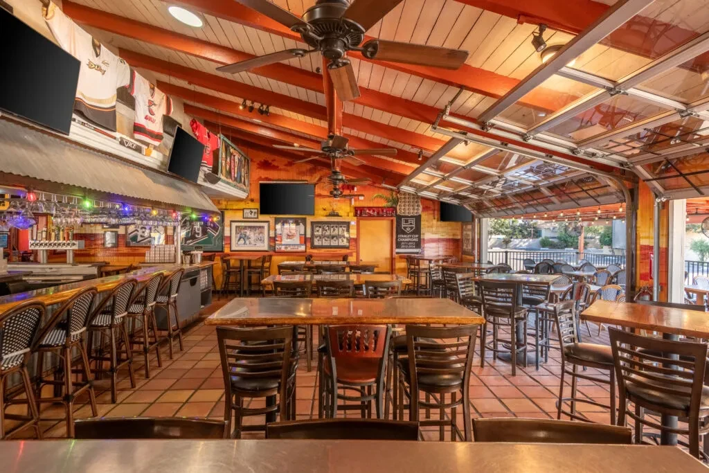 Lively sports bar interior with prominent bar and open garage door.