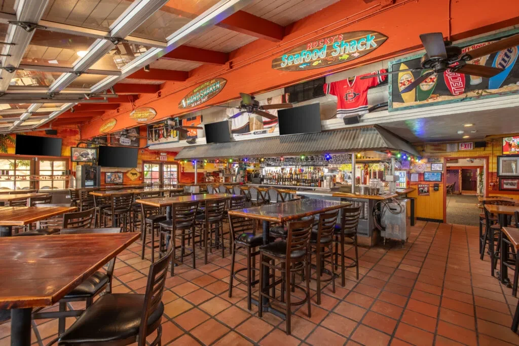 Empty, casual bar interior with beach and sports decor.