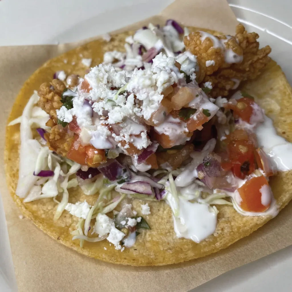 Fried fish taco with cabbage, pico de gallo, creamy sauce, and crumbled cheese.