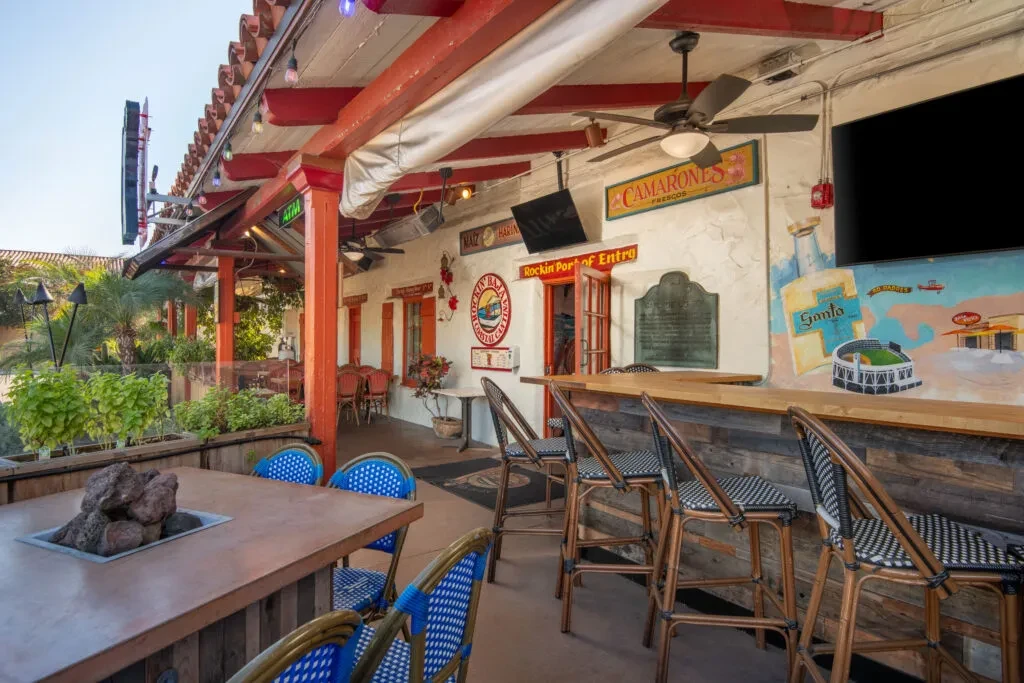 Outdoor restaurant patio and bar with fire pit and colorful wall mural.