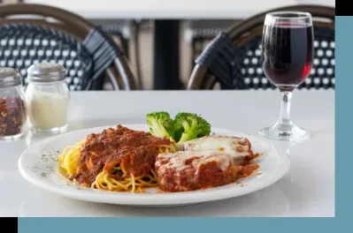 Spaghetti, parmesan, broccoli, red wine, and condiment shakers.