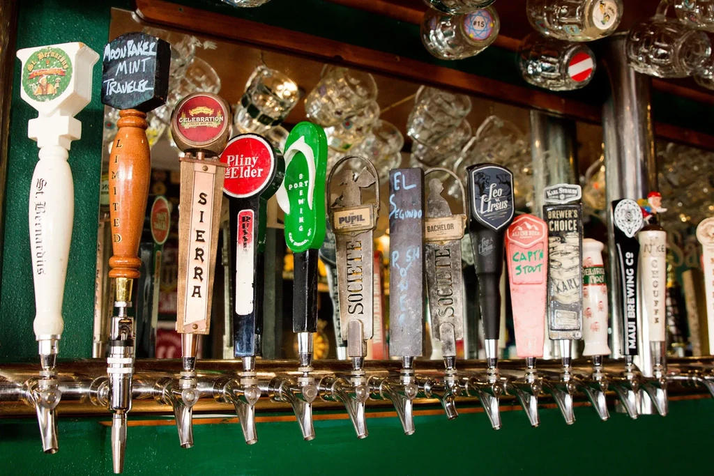 Numerous unique beer tap handles featuring various brands in a bar.