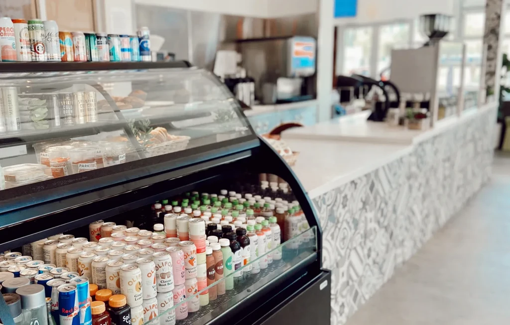Refrigerated display case filled with drinks and pastries in a modern cafe.