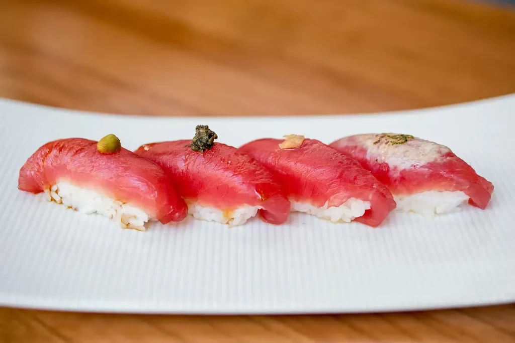 Row of four tuna nigiri sushi, each with a different topping.