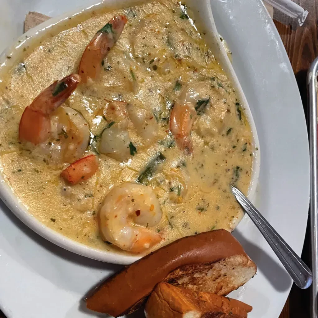 Creamy golden shrimp sauce with toasted bread, in a white bowl.