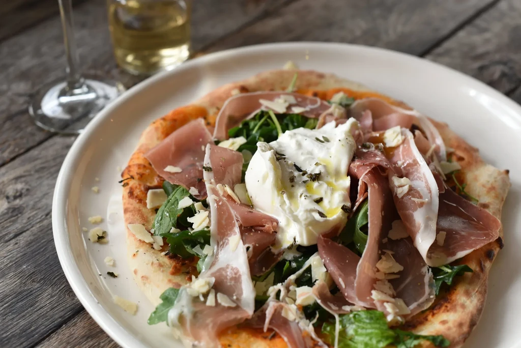 Neapolitan-style flatbread with prosciutto, arugula, and burrata cheese.
