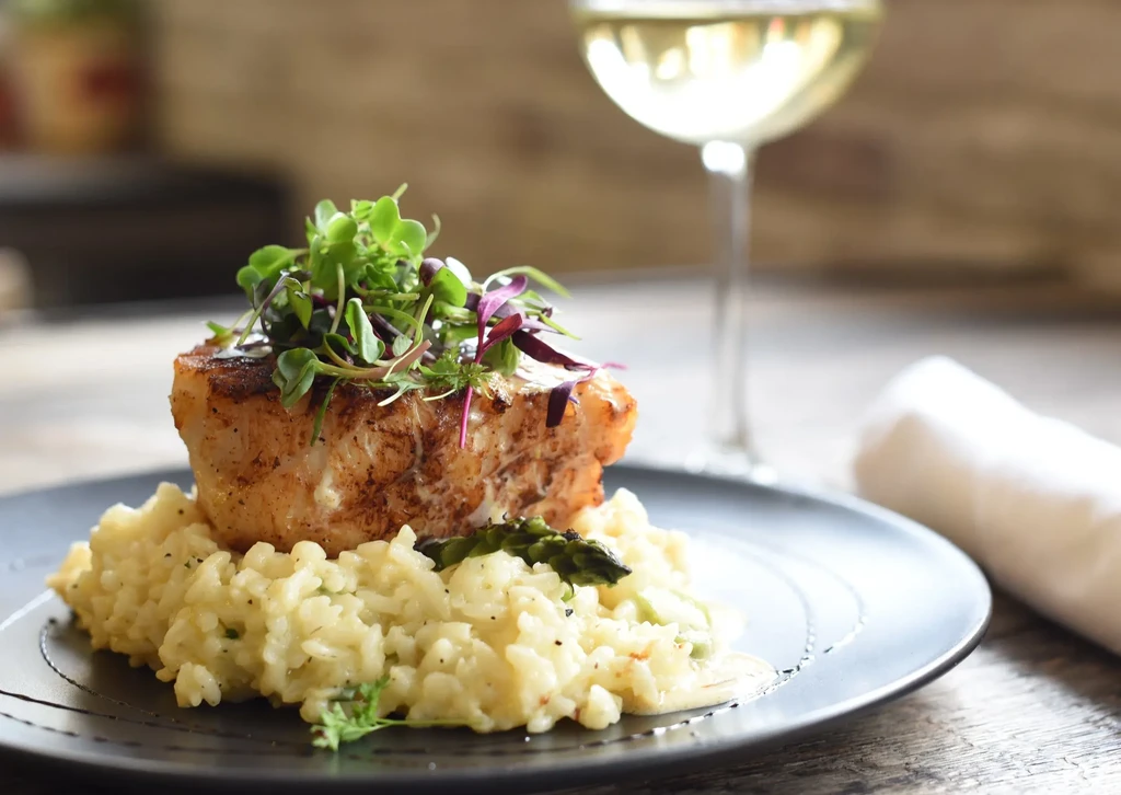 Pan-seared white fish on creamy risotto garnished with microgreens.