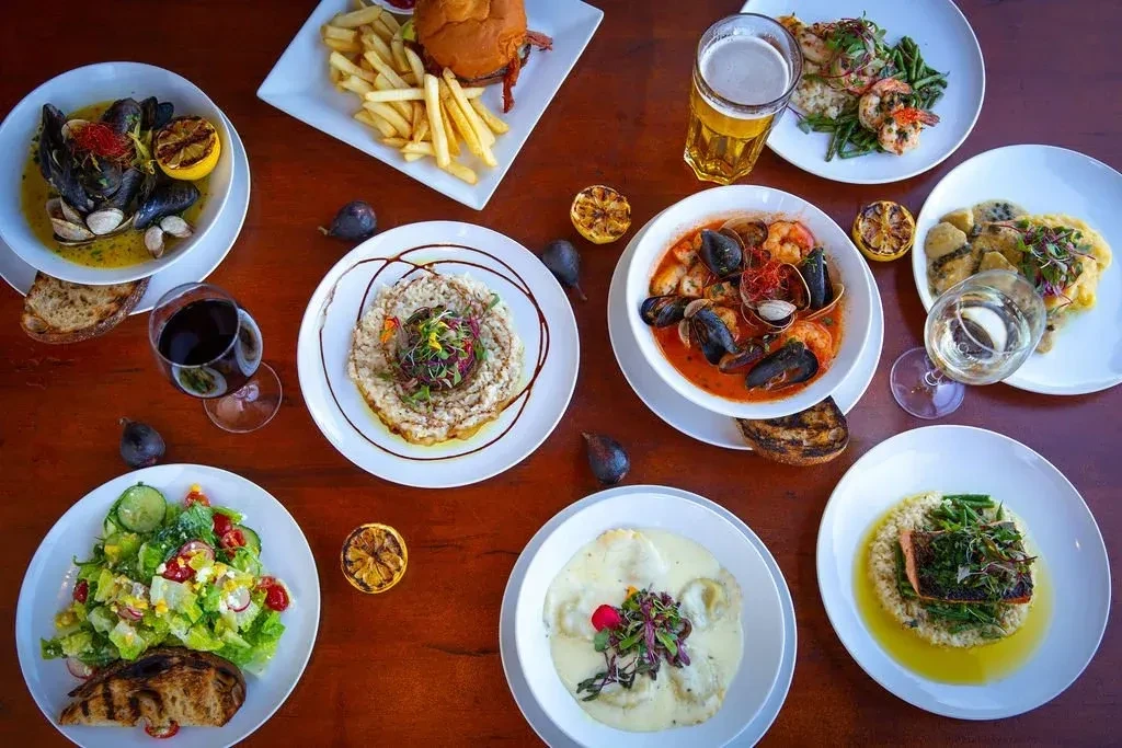 High-angle view of a wooden table covered with diverse food and drinks.