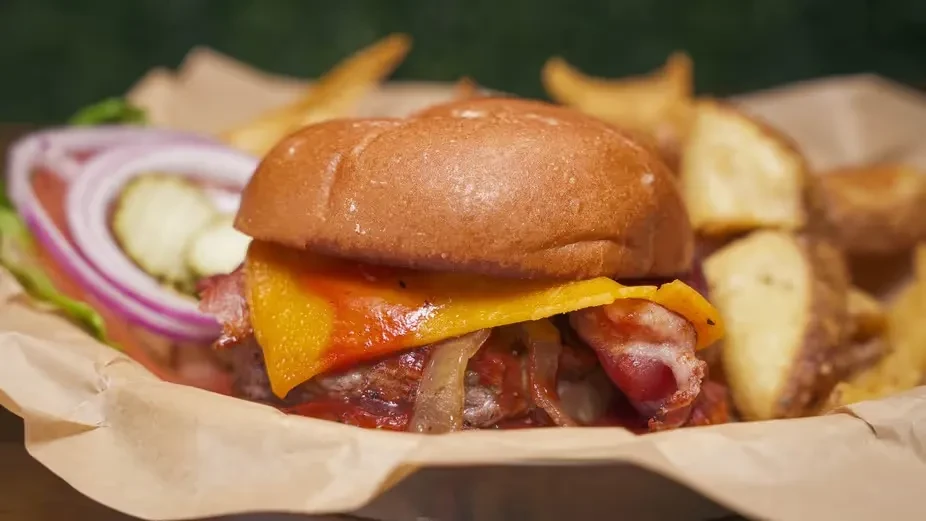 Gourmet hamburger with bacon, melted cheese, lettuce, potato wedges.