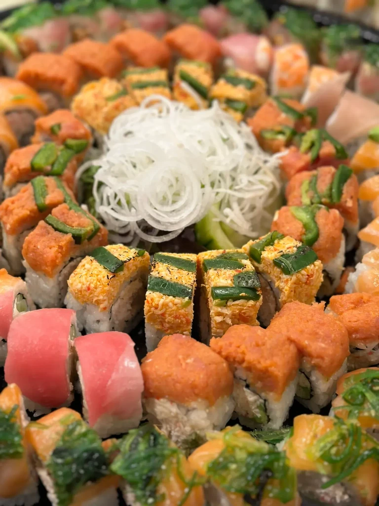 Assorted sushi and nigiri platter with salmon, tuna, and daikon garnish.