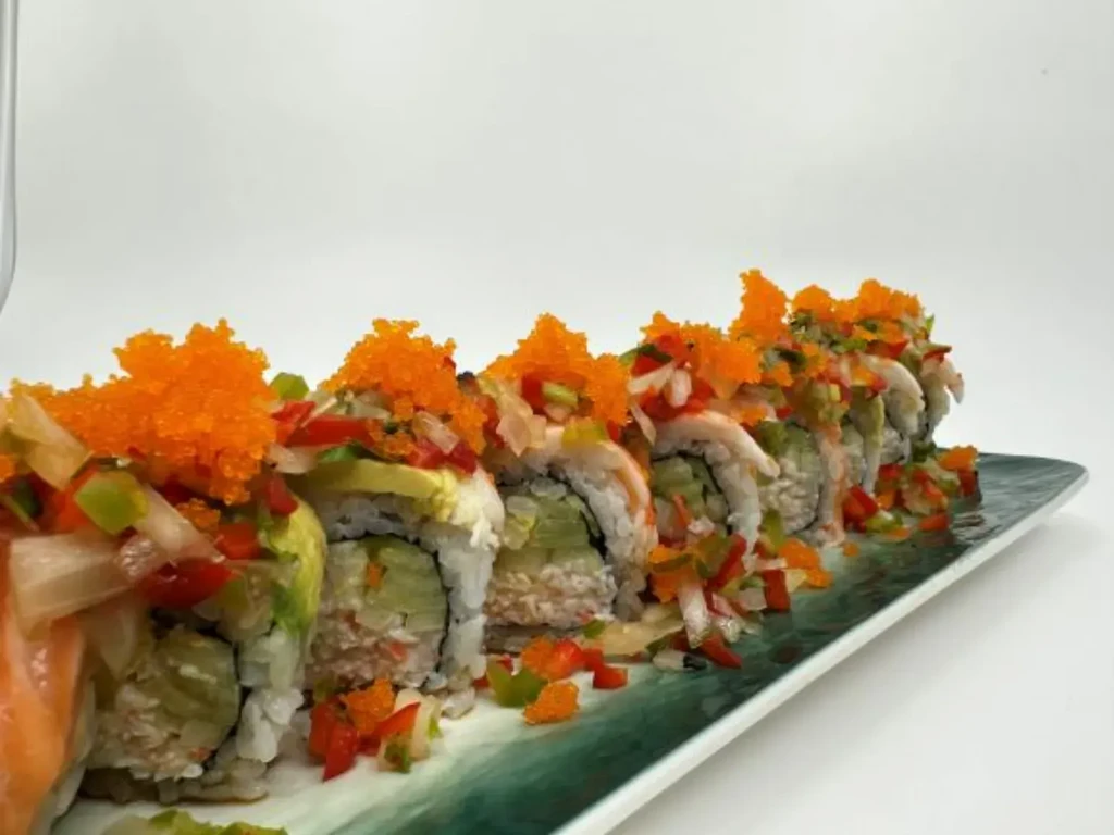 Sushi rolls topped with tobiko, colorful vegetables, and fish.