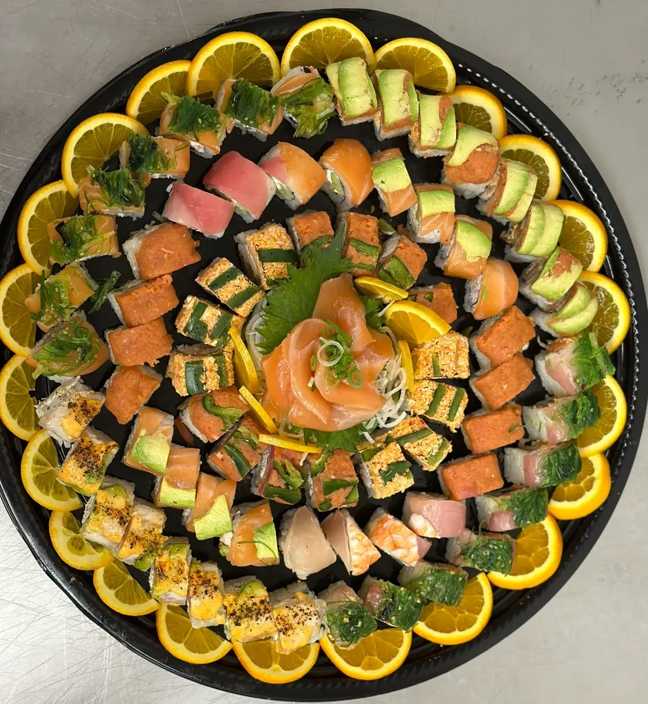 Large black platter with sushi, salmon sashimi, and orange slices.