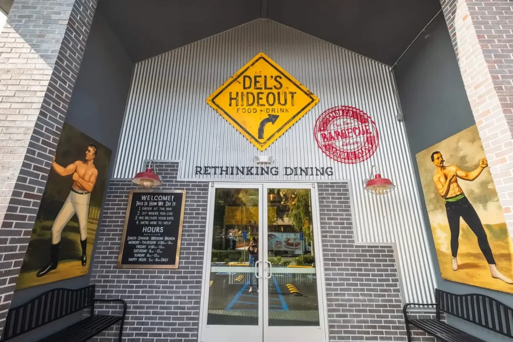 Del's Hideout restaurant building with strongman murals and diamond sign.