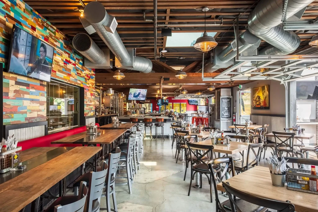 Empty, modern industrial-chic restaurant interior with colorful reclaimed wood wall.