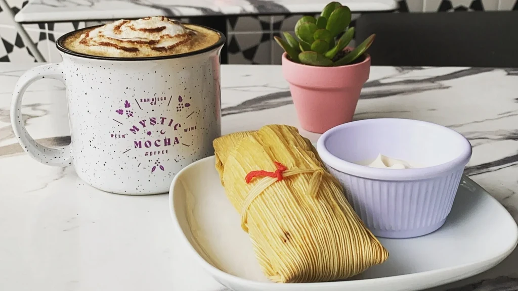 Frothy Mystic Mocha, corn husk tamale, and crema on marble table.
