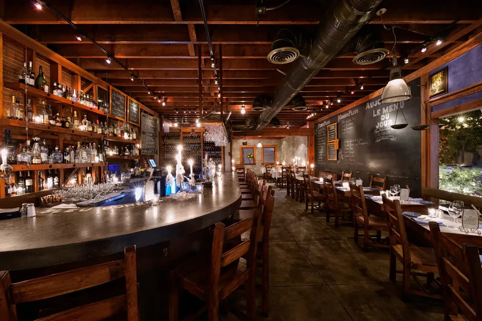 Industrial-chic bar and dining interior with concrete counter and French menus.