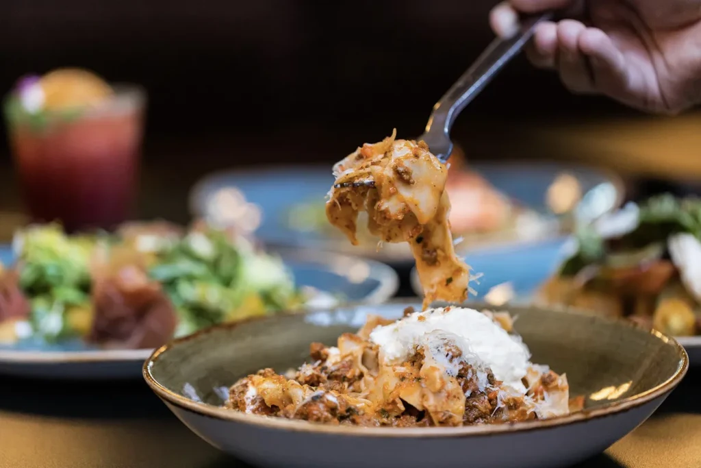Fork lifts saucy, cheesy pasta from a rustic bowl in a restaurant.