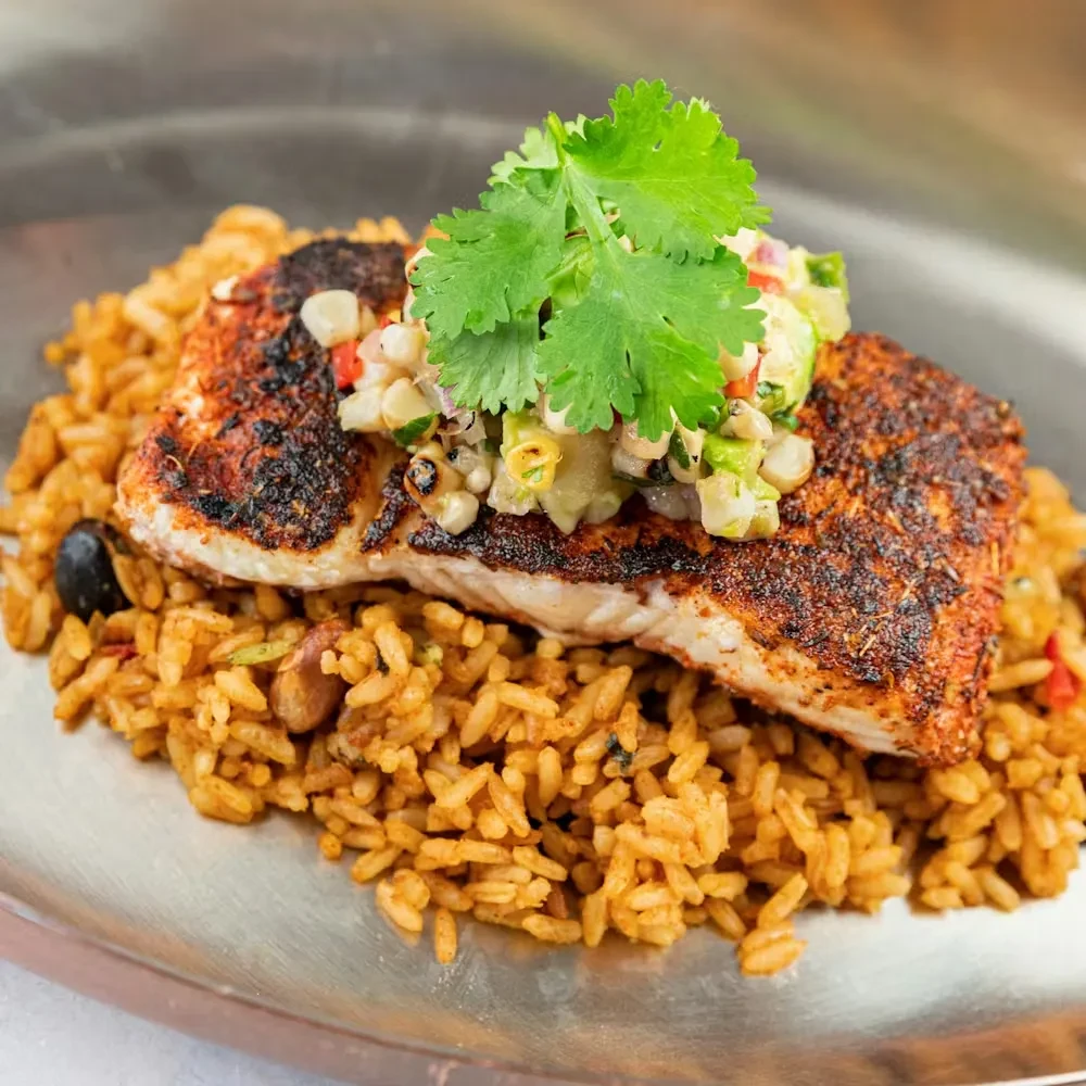 Grilled fish with colorful corn salsa on fluffy Spanish rice.