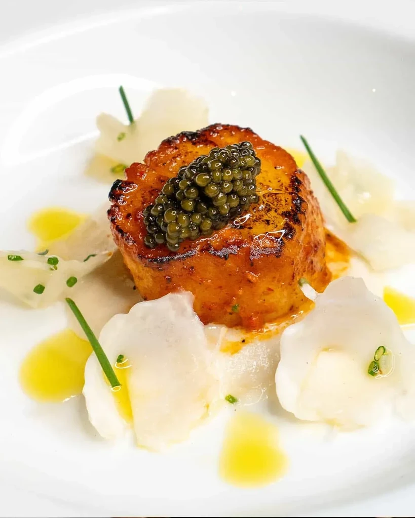 Artistically plated seared dish with green caviar and delicate garnishes.