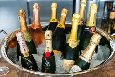 Large silver ice bucket with many champagne bottles on ice.