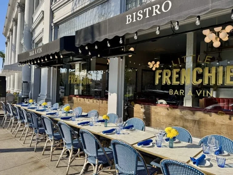 Little Frenchie Bistro's outdoor dining with blue chairs and yellow flowers.