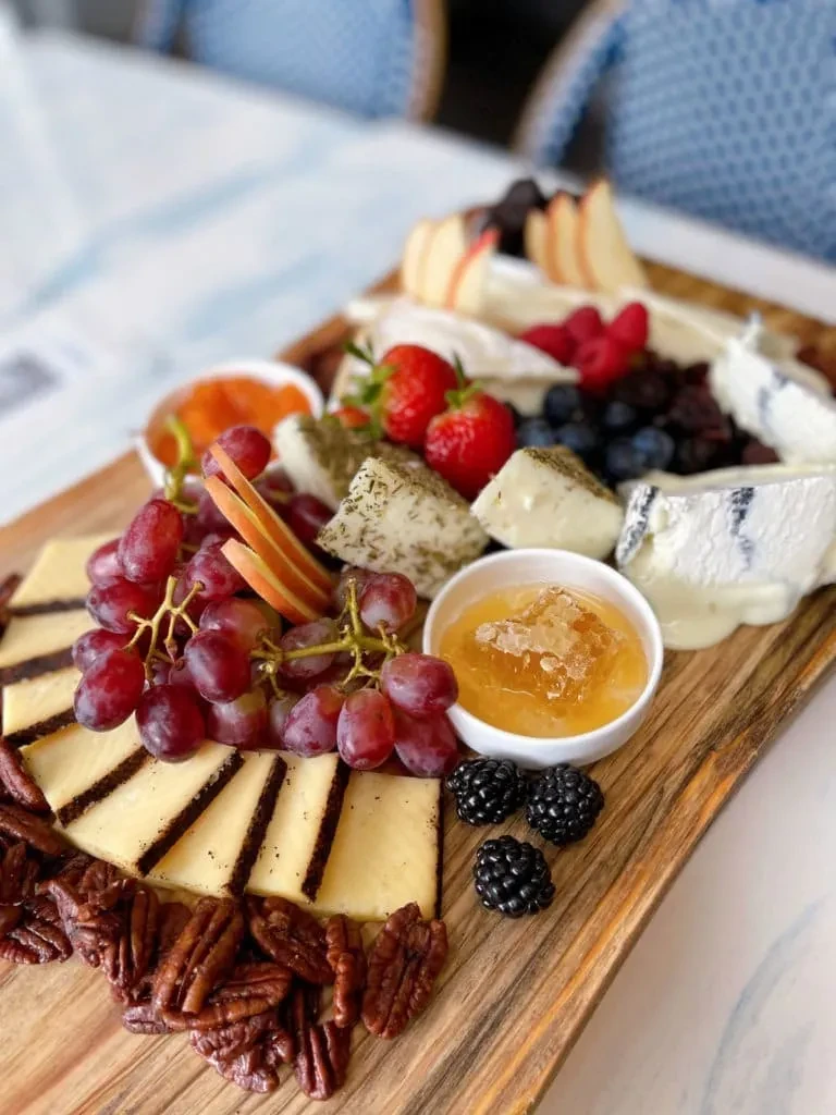 Close-up of a charcuterie and cheese board with fruit, nuts, and honeycomb.