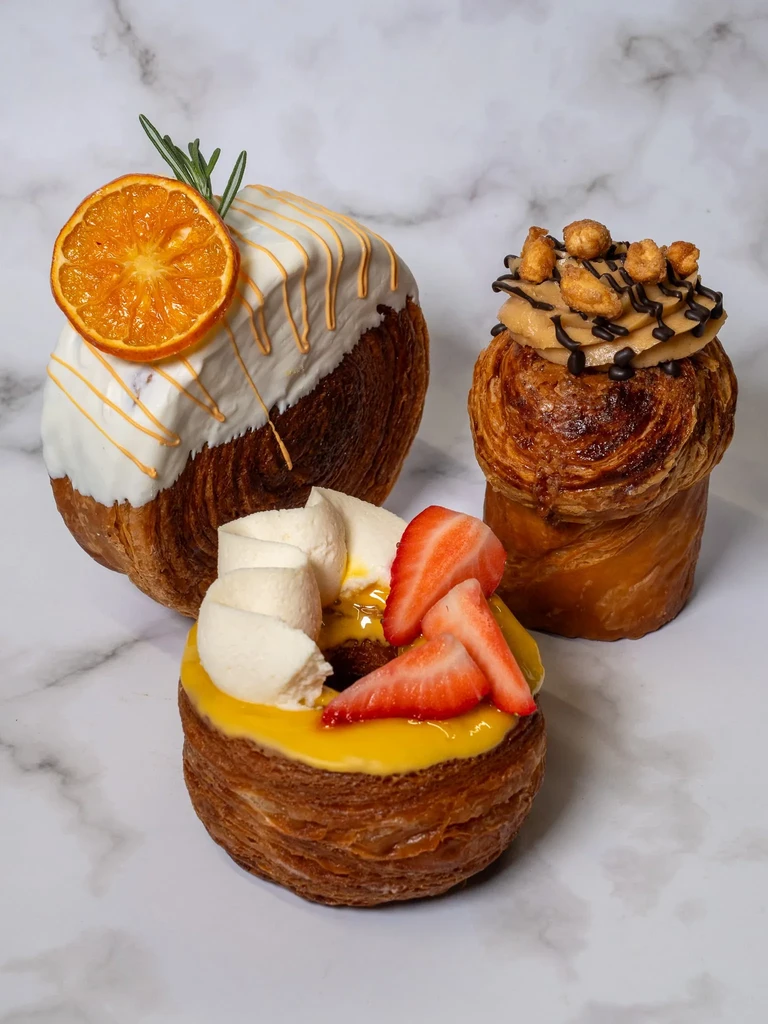 Three gourmet pastries artfully arranged on a white marble surface.