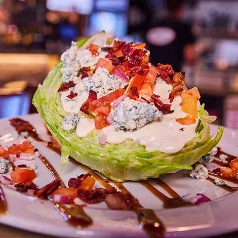 Wedge salad with blue cheese, bacon, tomatoes, and balsamic glaze.