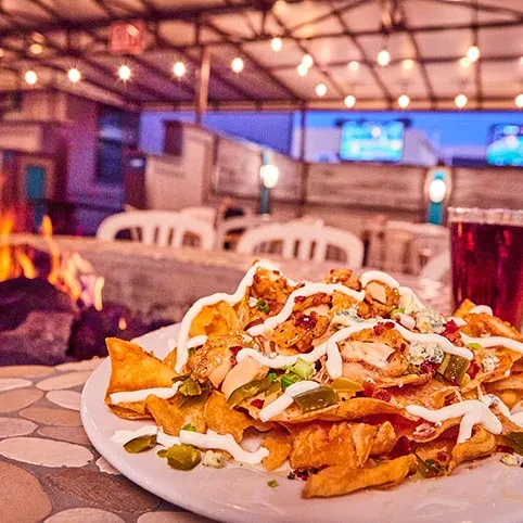 Close-up of loaded chicken nachos with blue cheese, jalapeños, outdoors.