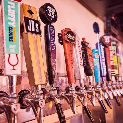 Close-up of a row of diverse, branded beer tap handles.